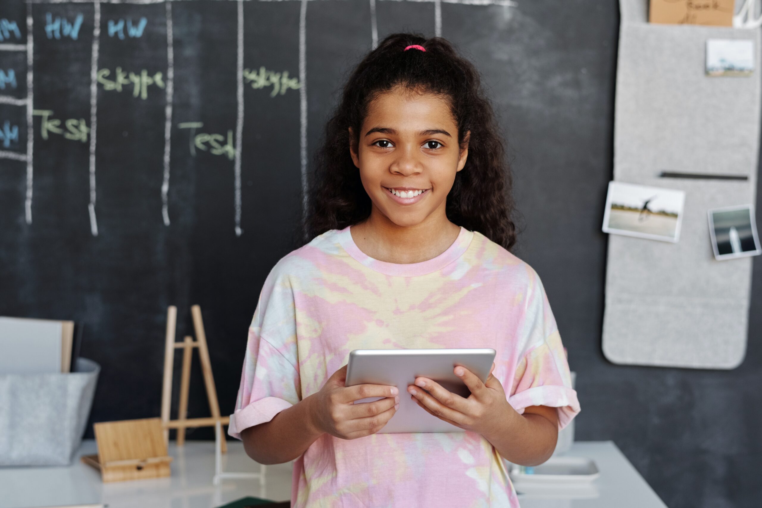 Smiling child holding a tablet in a classroom